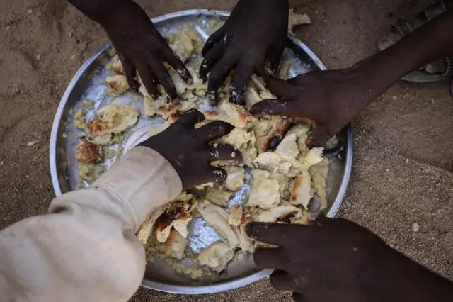 أطفال لاجئون سودانيون من الفاشر يتقاسمون وجبة مجانية في مخيم تينة شرقي تشاد، بعدما فروا من الحرب المستمرة في السودان.