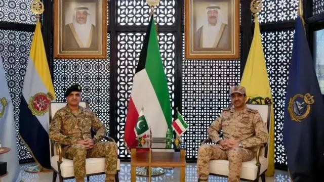 مسؤلان بارزان من الكويت وباكستان بلباس عسكري وخلفهما علما بلادهما.
