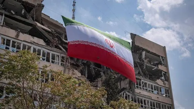 العلم الإيراني معلق على مقر السلطة القضائية في طهران، والذي تضرر في عملية عسكرية في 20 أبريل/نيسان 2026. 