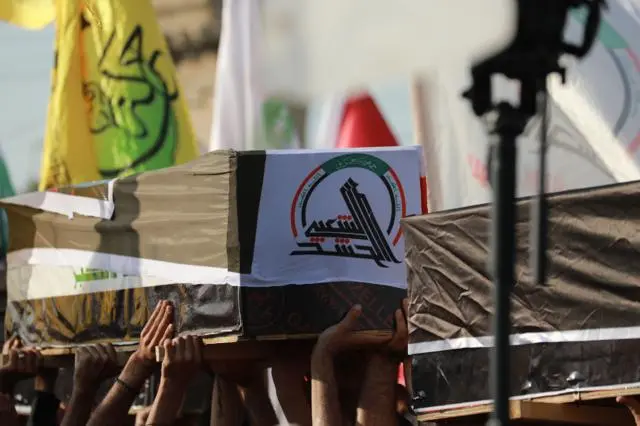 نعوش مغطاة بالعلمين العراقي والإيراني خلال تشييع عناصر من الحشد الشعبي في بغداد، بعدما قالت الهيئة إن الغارات أودت بحياة عشرين من عناصرها وأصابت 32 آخرين.
