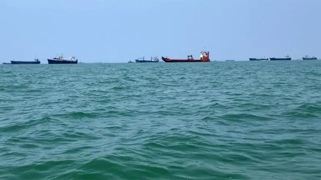 ما لا يقل عن عشر سفن كبيرة في عرض البحر، وسط مياه متقلبة بعض الشيء وسماء زرقاء.