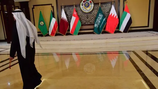 رجل يمرّ أمام أعلام الدول المشاركة في قمة مجلس التعاون الخليجي في قصر بيان بمدينة الكويت، بتاريخ 5 ديسمبر/كانون الأول 2017.