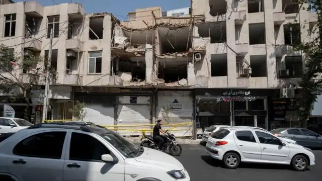 تمر مركبات ودراجة نارية أمام مبنى استُهدف ودُمر في غارة جوية أمريكية خلال الحملة العسكرية الأمريكية الإسرائيلية في طهران، إيران، في 21 يوليو/تموز 2026، وسط تجدد الصراعات بين إيران والولايات المتحدة في جنوب إيران.
