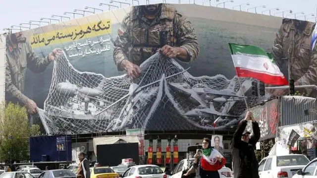 صورة لافتة كبيرة عُلّقت في طهران، كُتب عليها: "سيظل مضيق هرمز مغلقًا؛ والخليج بأكمله أرض صيد لنا"، وتُظهر جنوداً يحملون شبكة صيد، علقت بها ناقلات نفط وطائرات عسكرية. في المقدمة سيارات وأشخاص يحملون أو يلوحون بالأعلام الإيرانية.