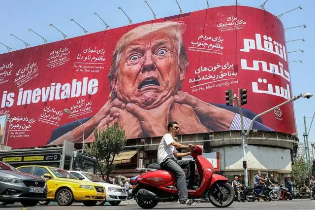 يقود سائقون سياراتهم بجانب لوحة إعلانية ضخمة تتوعد بالانتقام من الرئيس الأمريكي دونالد ترامب، في شارع جمهوري وسط طهران، في 27 يوليو/تموز 2026.